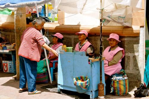 a group of women in pink hats sitting under an umbrella at Community Hostel Alausi in Alausí