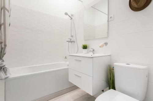 een witte badkamer met een wit bad en een toilet bij Studio proche Jean Moulin, location courte durée in Béziers