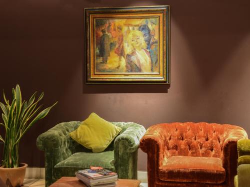 a living room with two chairs and a painting at Boutique Hotel Die Swaene in Bruges