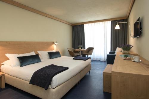 ein Hotelzimmer mit einem großen Bett und einem Tisch in der Unterkunft Hotel Meublè Sertorelli Reit in Bormio