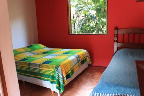 a red room with a bed and a window at Pousada O Canto das Sereias in Trindade