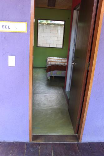 a hallway with a door open to a room with a bed at Pousada O Canto das Sereias in Trindade
