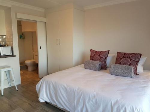 a bedroom with a white bed with two pillows on it at San Norina Gardens in Bloubergstrand
