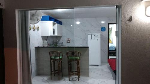 cocina con 2 taburetes y nevera en Flat La Piazzetta, en Pipa