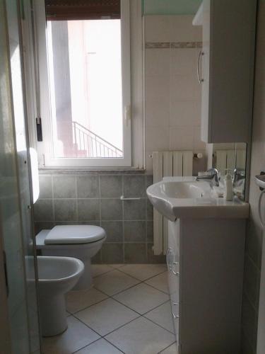 een badkamer met een wastafel, een toilet en een raam bij Scarpone in Pavia