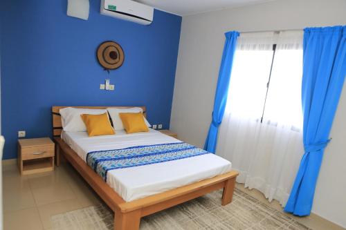Un dormitorio con una cama con paredes azules y una ventana en Residence Alizee, en Abiyán