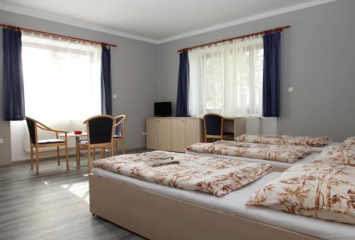 a bedroom with four beds and a table and chairs at Penzion Markéta Chrudim in Chrudim