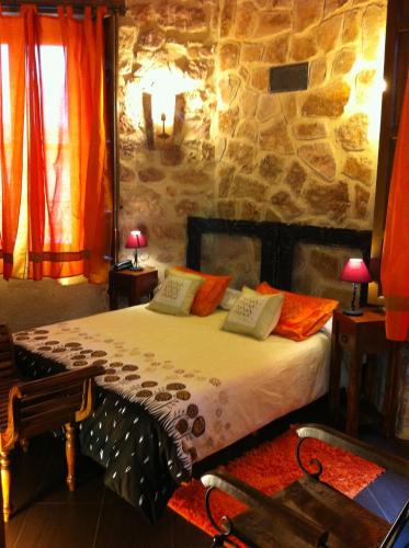 a bedroom with a bed and a stone wall at El Señorio De La Serrezuela in Aldeanueva De La Serrezuela 