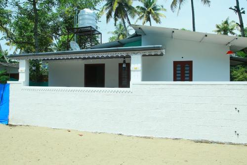 a house on the beach with a white wall at Marari Anandu Beach Villa in Mararikulam