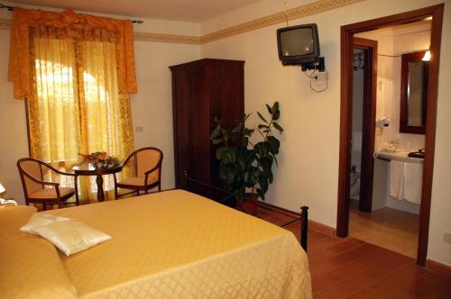 a bedroom with a bed and a table and a television at Hotel Borgo degli Olivi in Riotorto