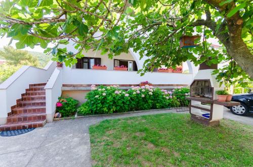 a house with a garden and a tree at Apartment Neda in Punat