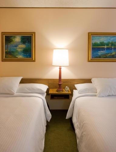 two beds in a hotel room with a lamp at Sunset Motel Moriarty in Moriarty