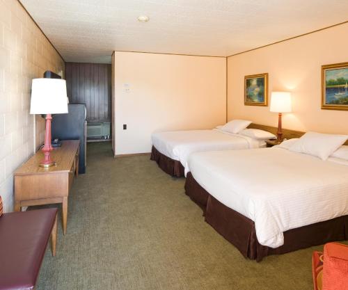 a hotel room with two beds and a television at Sunset Motel Moriarty in Moriarty