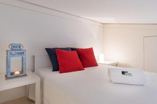 una camera da letto con un letto bianco con cuscini rossi e blu di BmyGuest - Quinta do Lago Mezzanine Apartment a Almancil