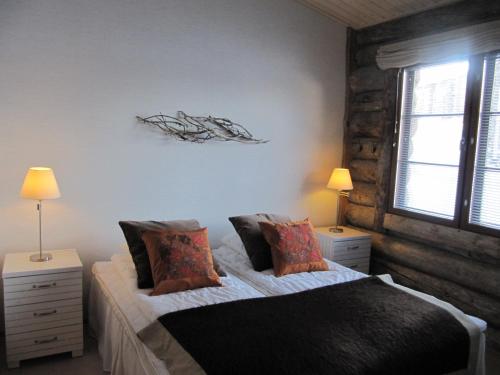 サーリセルカにあるLapin Kutsu Log Cabinsのベッドルーム1室(ベッド1台、ナイトスタンド2台、ランプ2つ付)