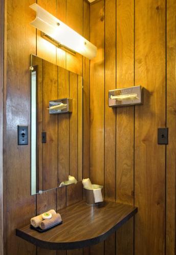 a bathroom with a mirror and a wooden wall at Sunset Motel Moriarty in Moriarty