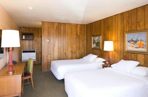 a hotel room with two beds and a desk at Sunset Motel Moriarty in Moriarty
