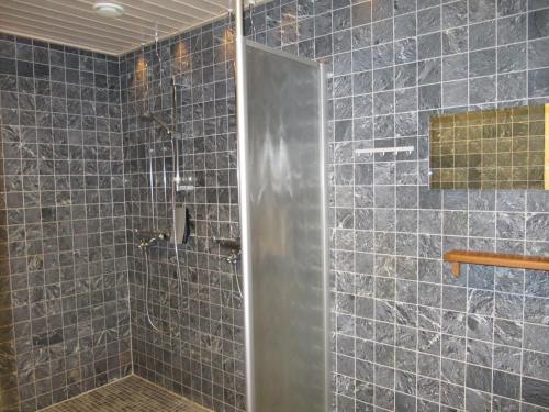 a bathroom with a shower with blue tiles at Lapin Kutsu Log Cabins in Saariselka