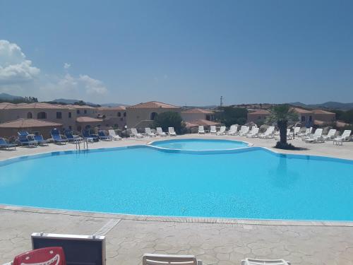 une grande piscine bleue avec des chaises et des chaises dans l'établissement Sardinia Beach Apartments, à Aglientu