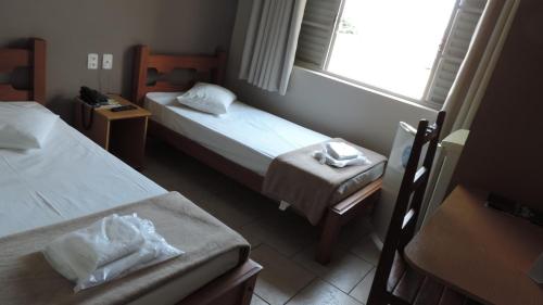 a small room with two beds and a window at Presidente Hotel in Passos