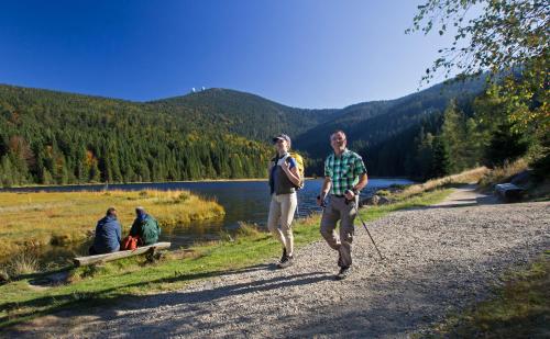 two men walking down a gravel road next to a lake at Hotel Amberger Hof in Bad Koetzting