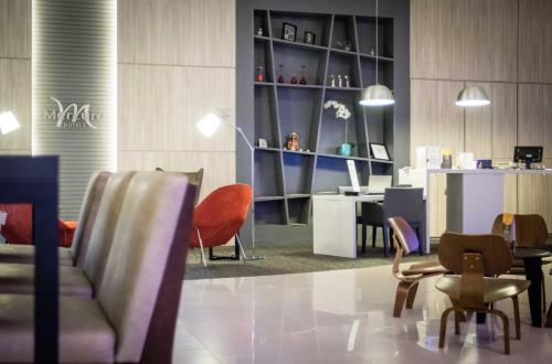 a lobby with chairs and a table and a desk at Mercure Sao Jose dos Campos in São José dos Campos