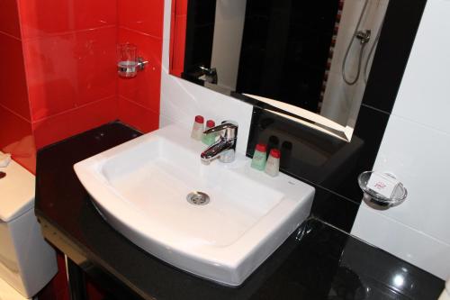 a white sink in a bathroom with a red wall at Hotel Dunav in Vidin