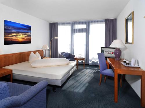 a hotel room with a bed and a desk at Hotel Excelsior Ludwigshafen in Ludwigshafen am Rhein