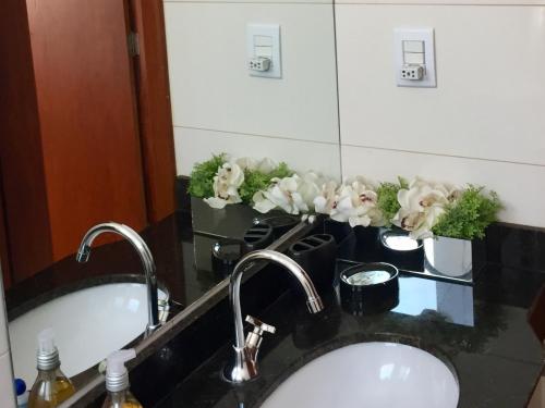 a bathroom sink with white flowers on a counter at Apartamento 3 Quartos com varanda in Diamantina