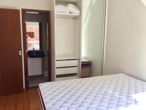 - une chambre avec un lit blanc et un placard dans l'établissement Apartamento 3 Quartos com varanda, à Diamantina