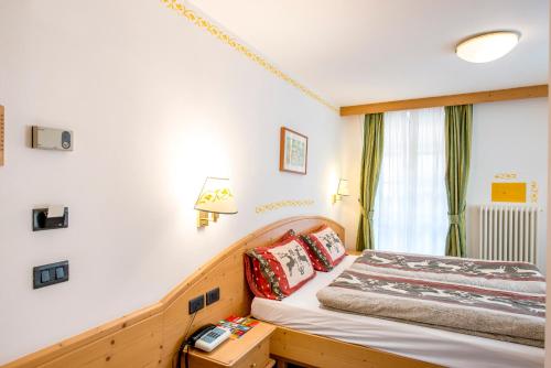 a bedroom with a bed and a window at Hotel Villa Rosella Park & Wellness in Canazei