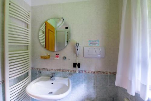 a bathroom with a sink and a mirror at Hotel Villa Rosella Park & Wellness in Canazei