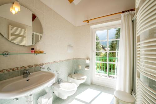 a bathroom with a sink and a toilet and a mirror at Hotel Villa Rosella Park & Wellness in Canazei