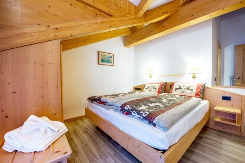 a bedroom with a bed in a room with wooden ceilings at Hotel Villa Rosella Park & Wellness in Canazei