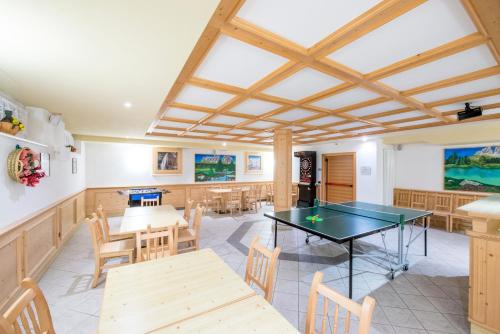 a dining room with a ping pong table and chairs at Hotel Villa Rosella Park & Wellness in Canazei