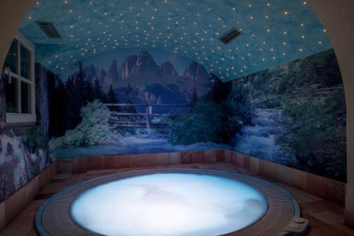 a jacuzzi tub in a room with a painting at Hotel Villa Rosella Park & Wellness in Canazei