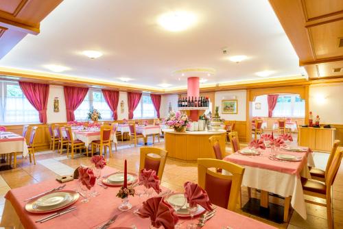 a dining room with tables and chairs with pink tablecloths at Hotel Villa Rosella Park & Wellness in Canazei