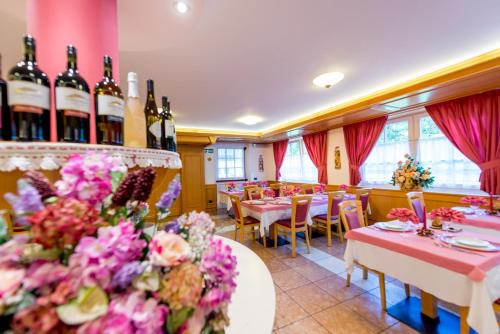 a restaurant with tables and bottles of wine at Hotel Villa Rosella Park & Wellness in Canazei