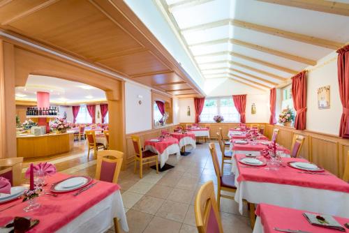 a restaurant with tables and chairs with red tablecloths at Hotel Villa Rosella Park & Wellness in Canazei