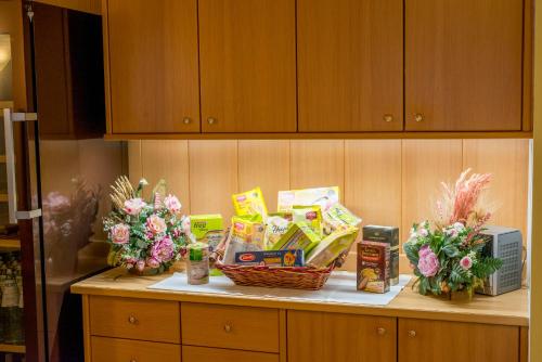 a kitchen counter with snacks and flowers on it at Hotel Villa Rosella Park & Wellness in Canazei