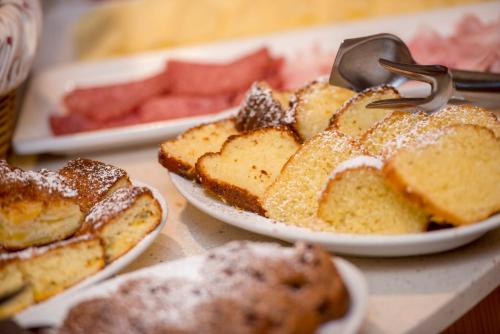 a table topped with plates of bread and watermelons at Hotel Villa Rosella Park & Wellness in Canazei