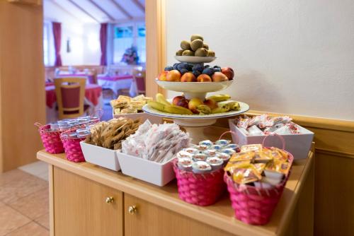 a buffet with a display of fruit and snacks at Hotel Villa Rosella Park & Wellness in Canazei