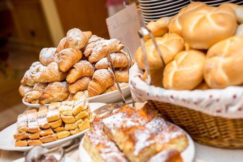 a table with plates of pastries and baskets of bread at Hotel Villa Rosella Park & Wellness in Canazei