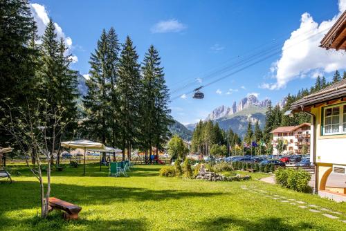 a park with a chair lift in the mountains at Hotel Villa Rosella Park & Wellness in Canazei