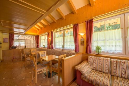a restaurant with a table and chairs and windows at Hotel Villa Rosella Park & Wellness in Canazei