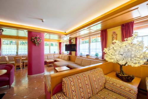 a large living room with couches and a tv at Hotel Villa Rosella Park & Wellness in Canazei