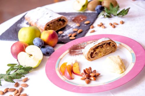 a plate with a piece of bread and fruit on a table at Hotel Villa Rosella Park & Wellness in Canazei