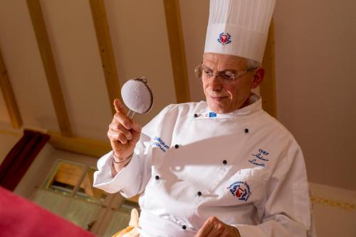 a chef holding a magnifying glass in a kitchen at Hotel Villa Rosella Park & Wellness in Canazei