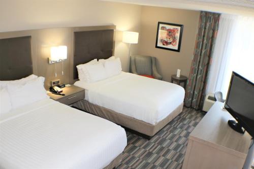 a hotel room with two beds and a flat screen tv at Holiday Inn Express Woodstock-Shenandoah Valley by IHG in Woodstock