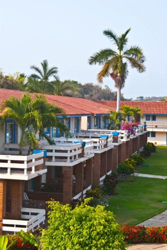 a building with white benches and a palm tree at Qualton Club Ixtapa All Inclusive in Ixtapa